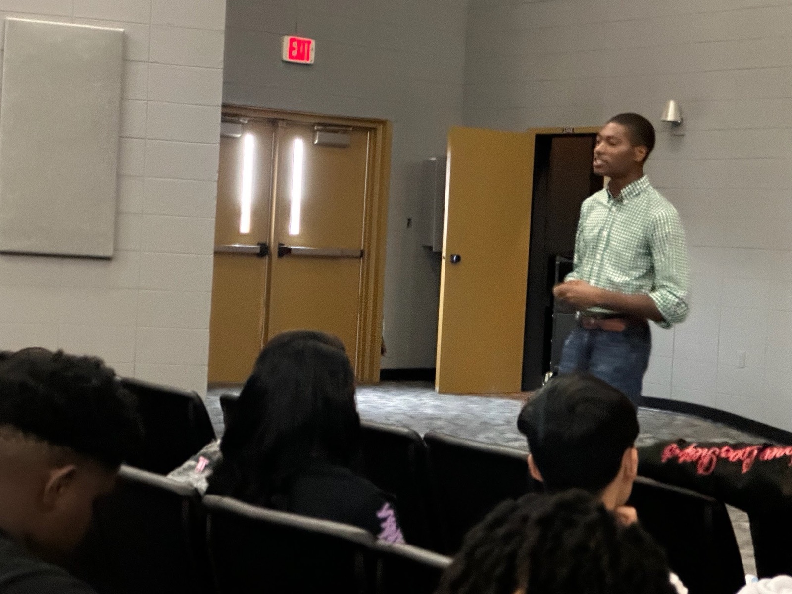 A young speaker presenting to a seated audience.