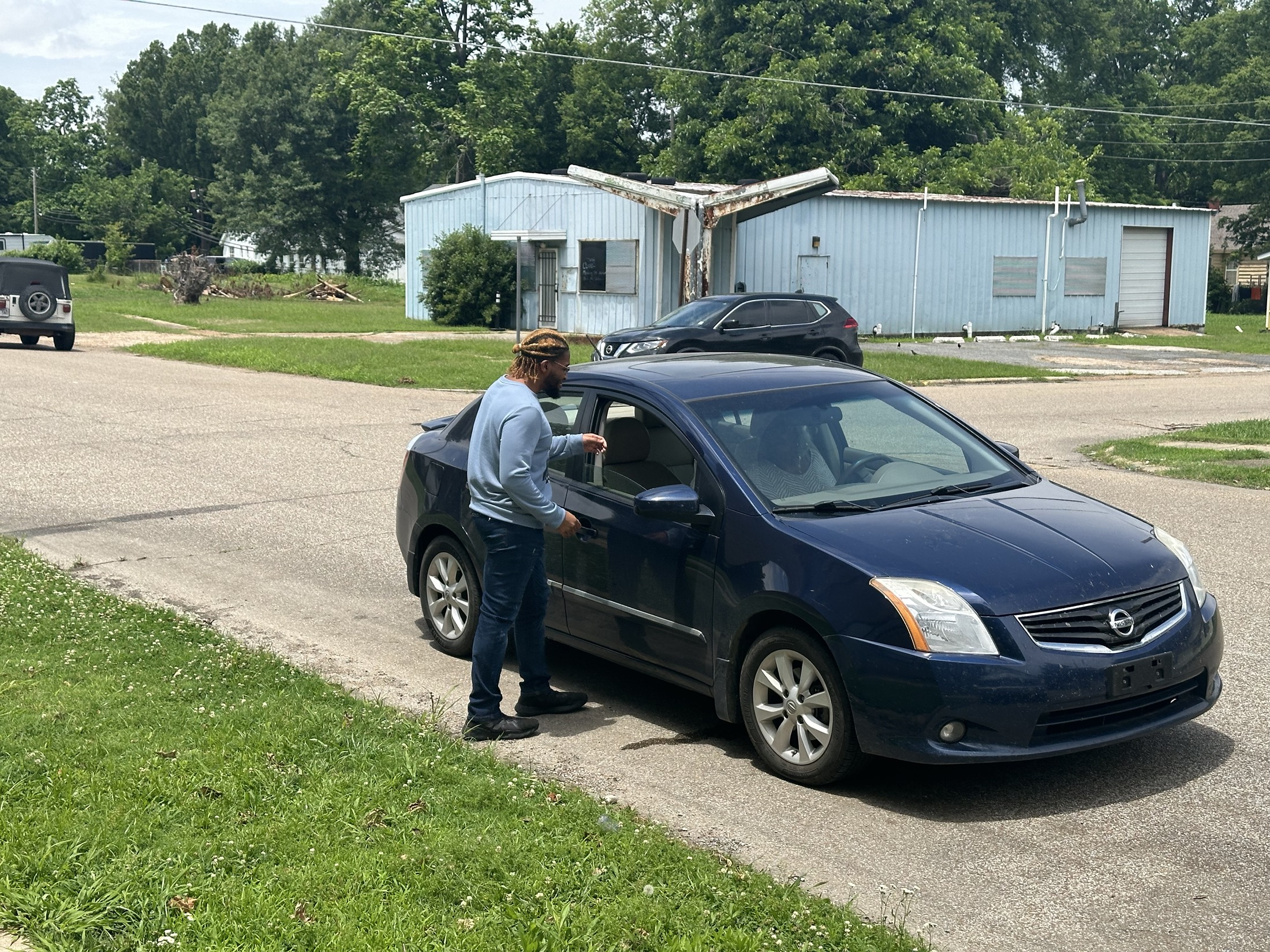 A driver opening a car door during a community transportation stop.